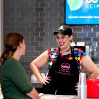 Worker at smoothie location smiling at customer from behind counter
